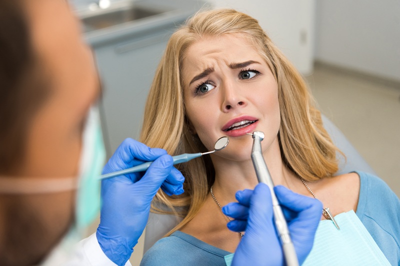 cropped shot of dentist examining teeth of frightened female client