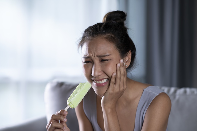 Young Asian woman have sensitive teeth with ice cream